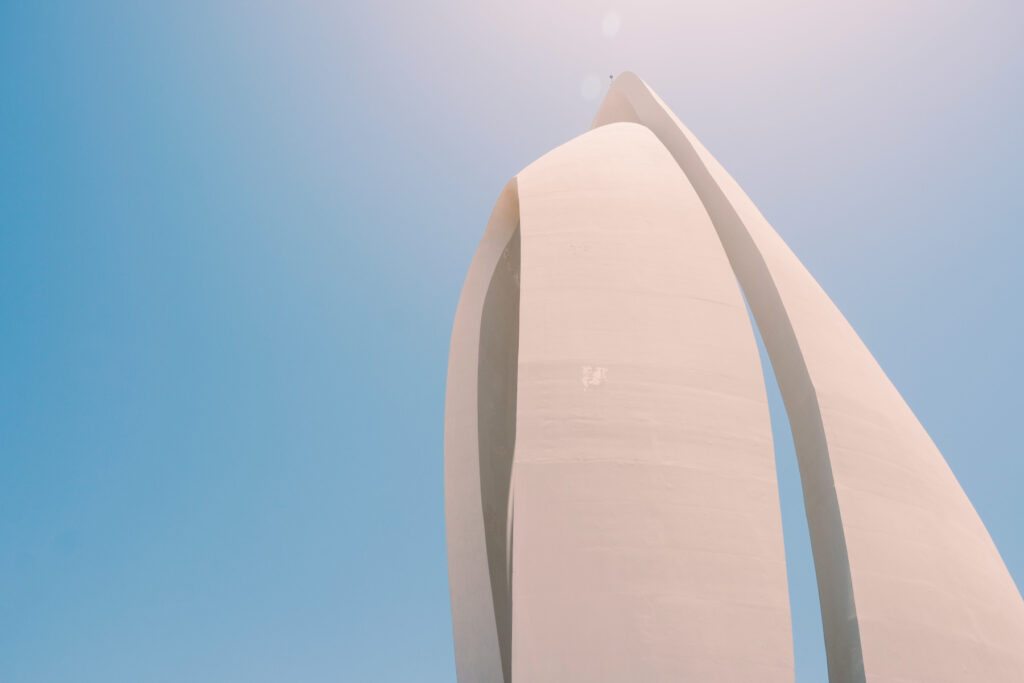 looking up at a tall white building with a blue sky in the background.